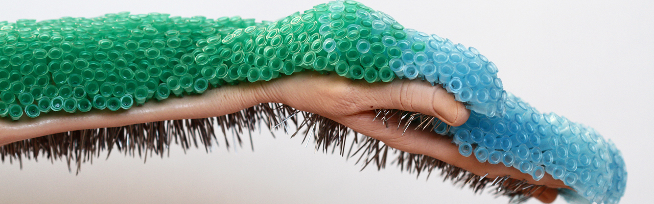 Hand extending horizontally holding hundreds of small blue and green needles